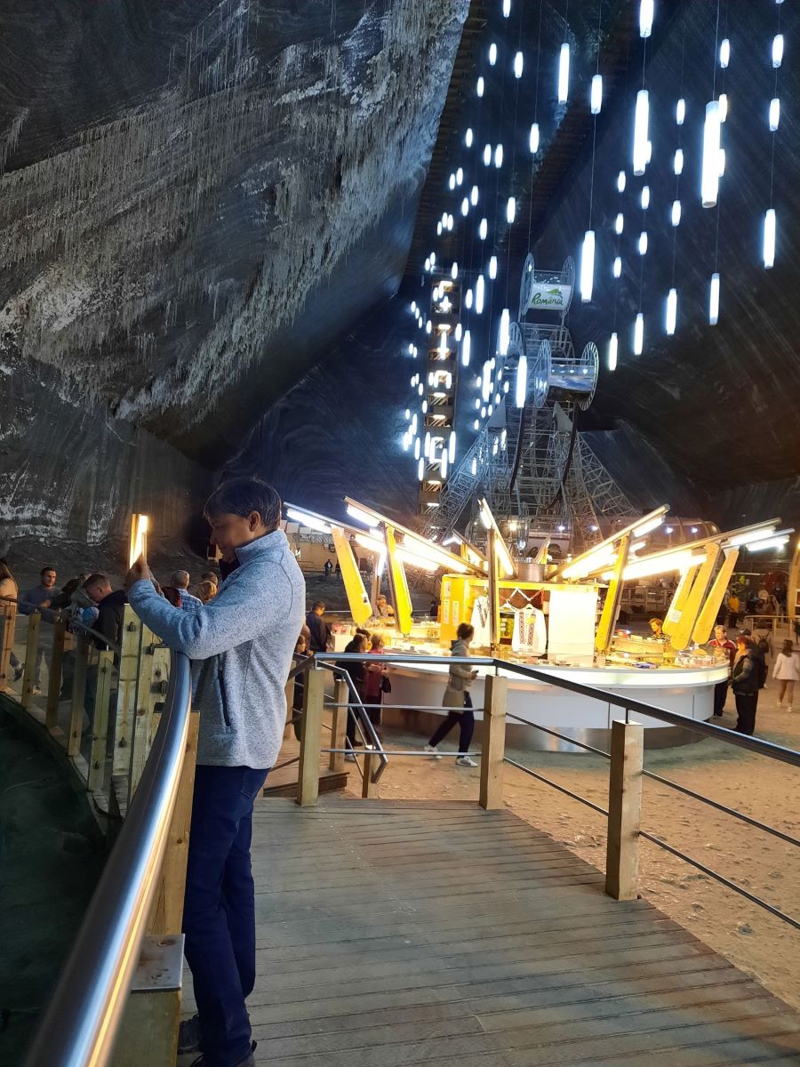 im Vordergrund steht Claudia in ihrer grauen Jacke und fotografiert in Richtung linken Bildrand. Im Hintergrund ist der Rudolfstollen der Salina Turda in Rumaenien zu sehen. 