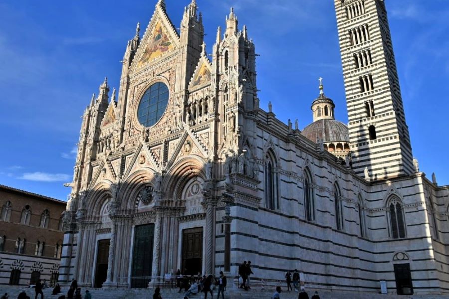 Blick auf den grün-weiß gestreiften Dom von Siena mit kunstvoller gotischer Fassade