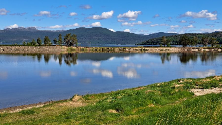 Spiegelung von Himmel und Bäumen im ruhigen Wasser am Campingplatz Solvang
