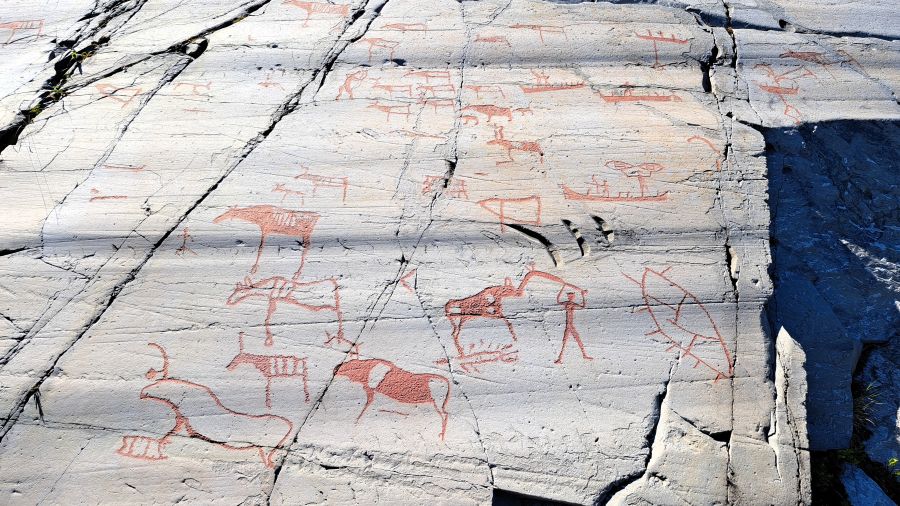 Rot nachgezeichnete Felsritzungen zeigen Rentiere, Boote und Menschen in Alta