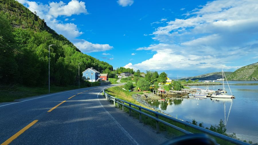 Straße am Langfjorden mit kleiner Marina und bunten Häusern