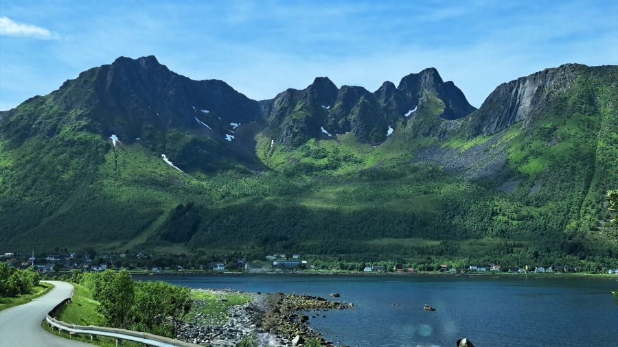 Straße entlang eines Fjords auf Senja mit steilen Bergen in Nordnorwegen