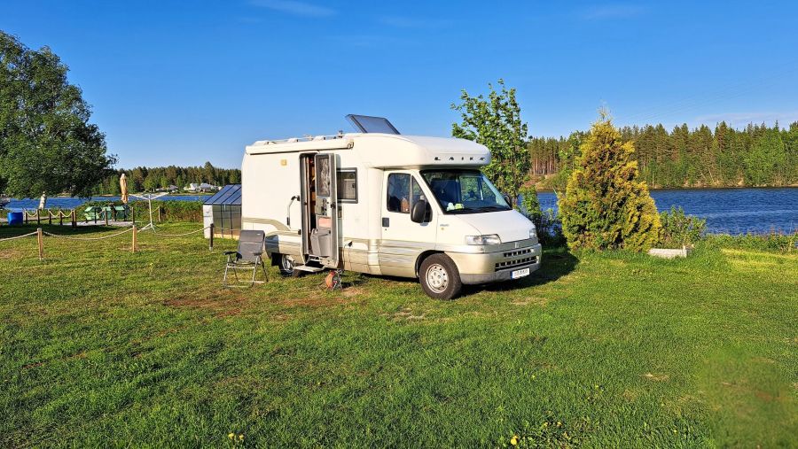 Wohnmobil auf grüner Wiese am Stellplatz in Hortlax bei Sonnenschein