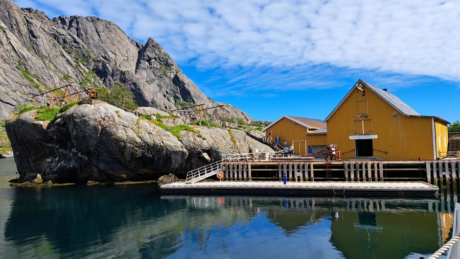 Gelbe Lagerhäuser am Hafen von Nusfjord zwischen Felsen und Meer
