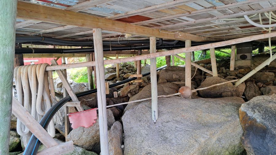 Holzpfähle und Felsfundament unter den historischen Häusern von Nusfjord