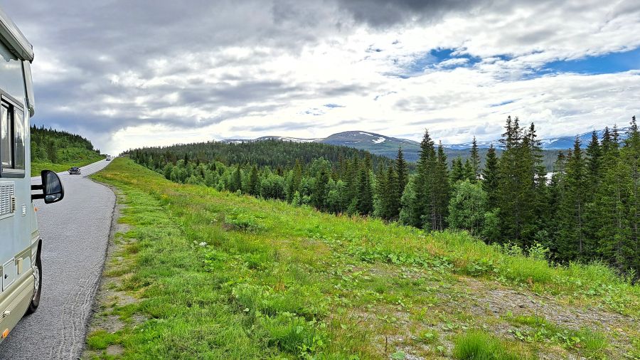 Wohnmobil an einer Straße durch die Berg- und Waldlandschaft Norwegens