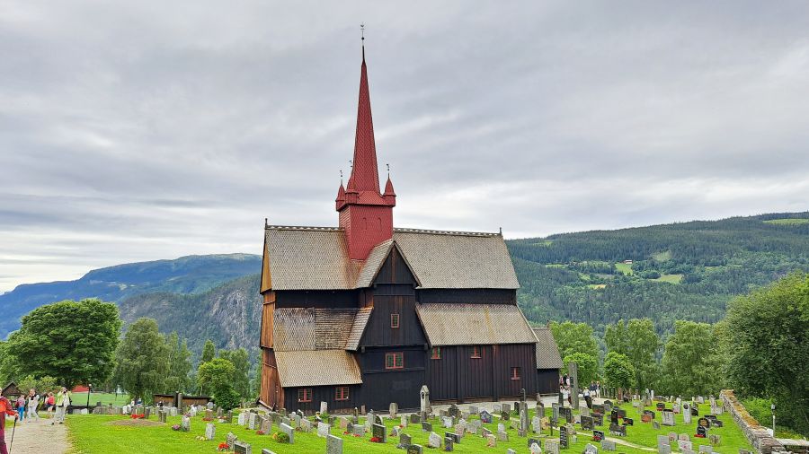 Ringebu Stabkirche mit Friedhof und Bergen im Hintergrund