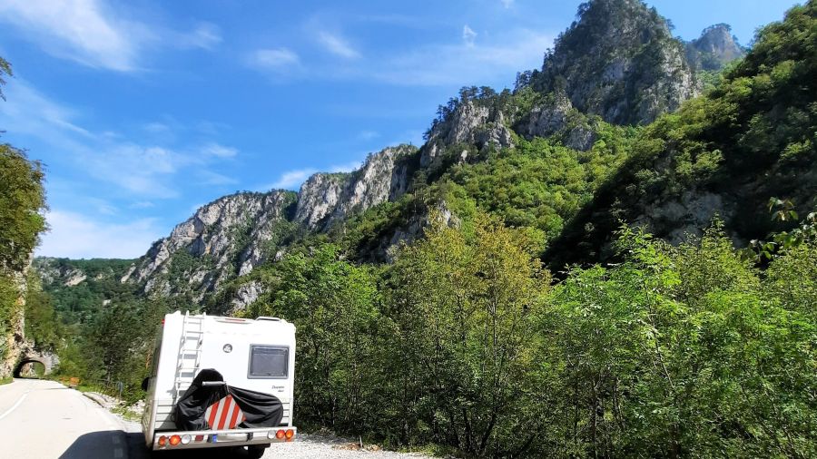 Wohnmobil auf der Straße durch bewaldete Felswände in der Tara-Schlucht